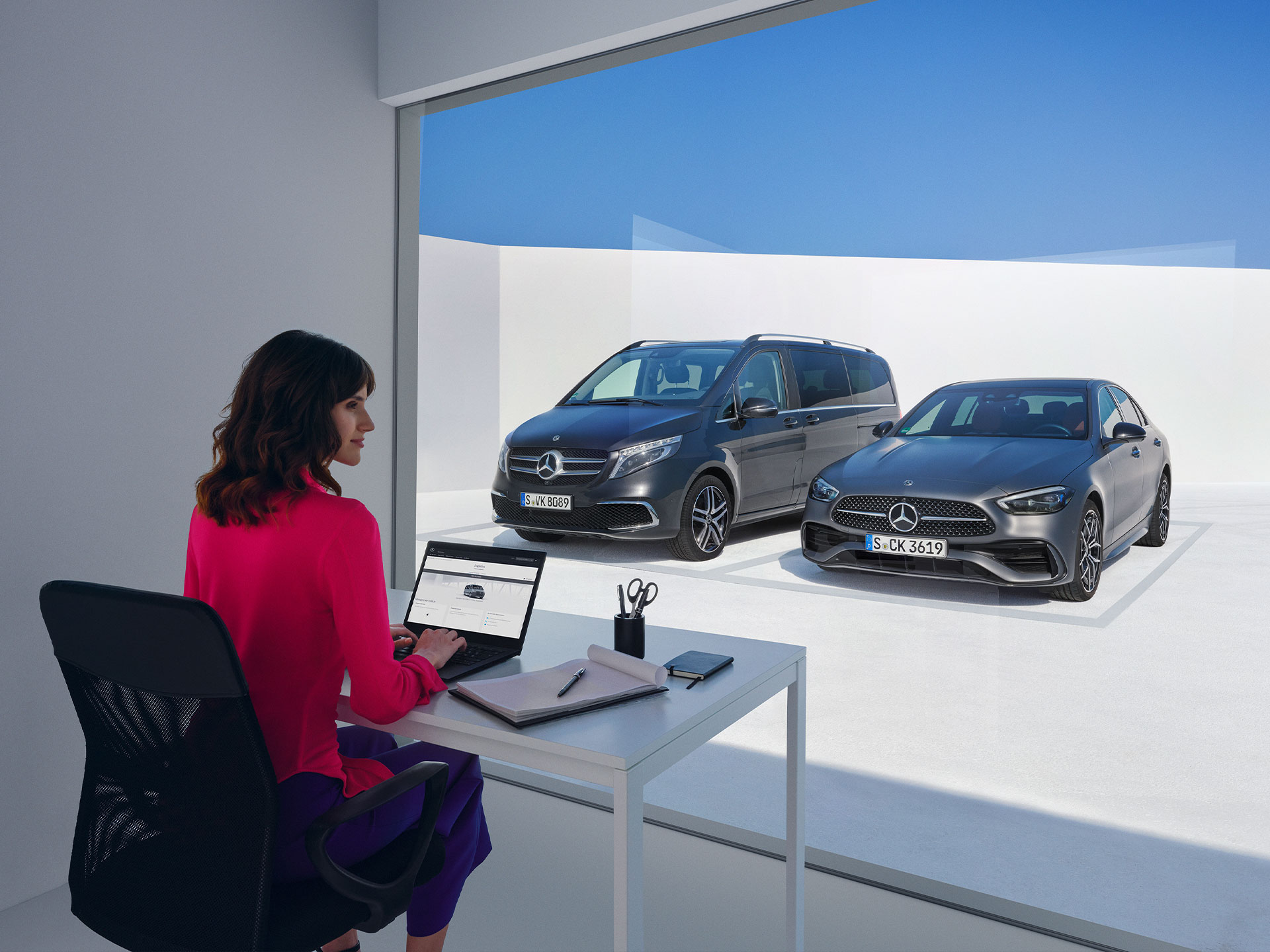 Extras digitales | Mercedes-Benz Mujeres sentadas delante del Mercedes-Benz Clase V y Clase C, mirando un ordenador portátil.