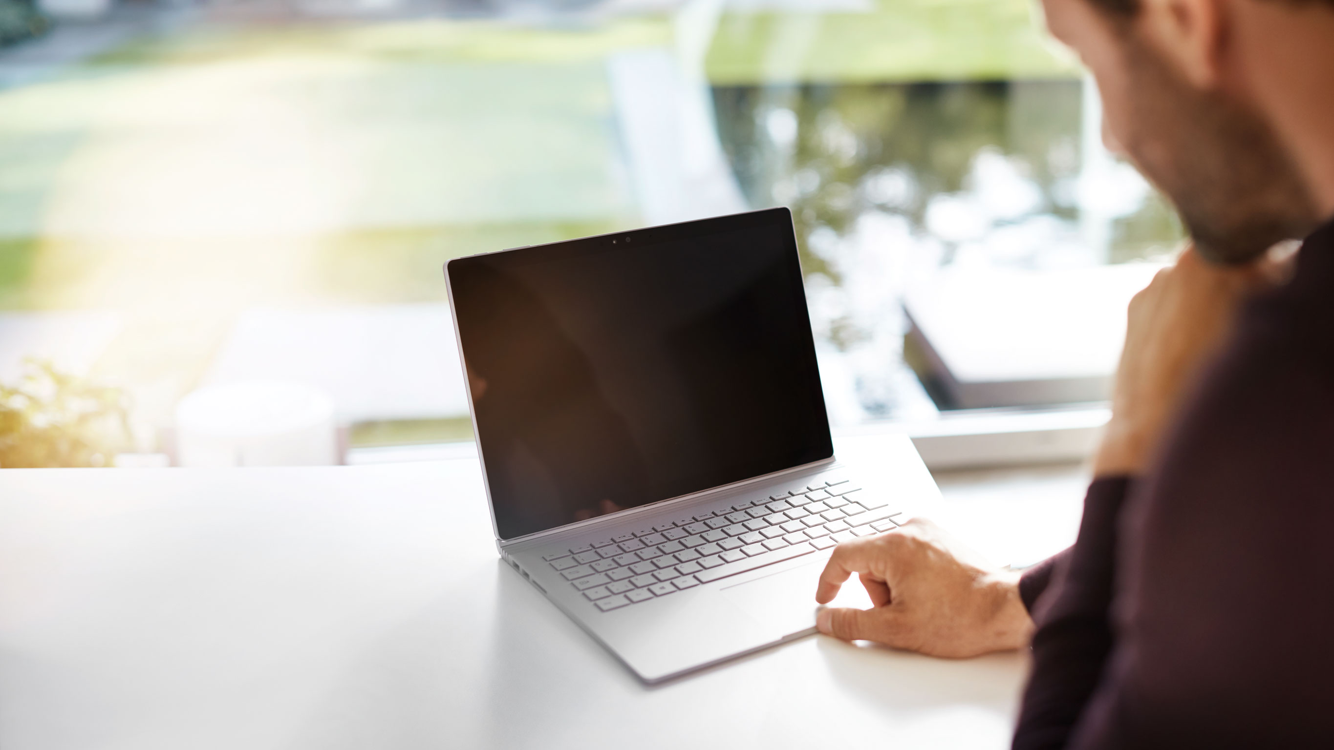 Trabajo eficiente con tecnología moderna Primer plano de un ordenador portátil sobre un escritorio con una persona acercándose a él