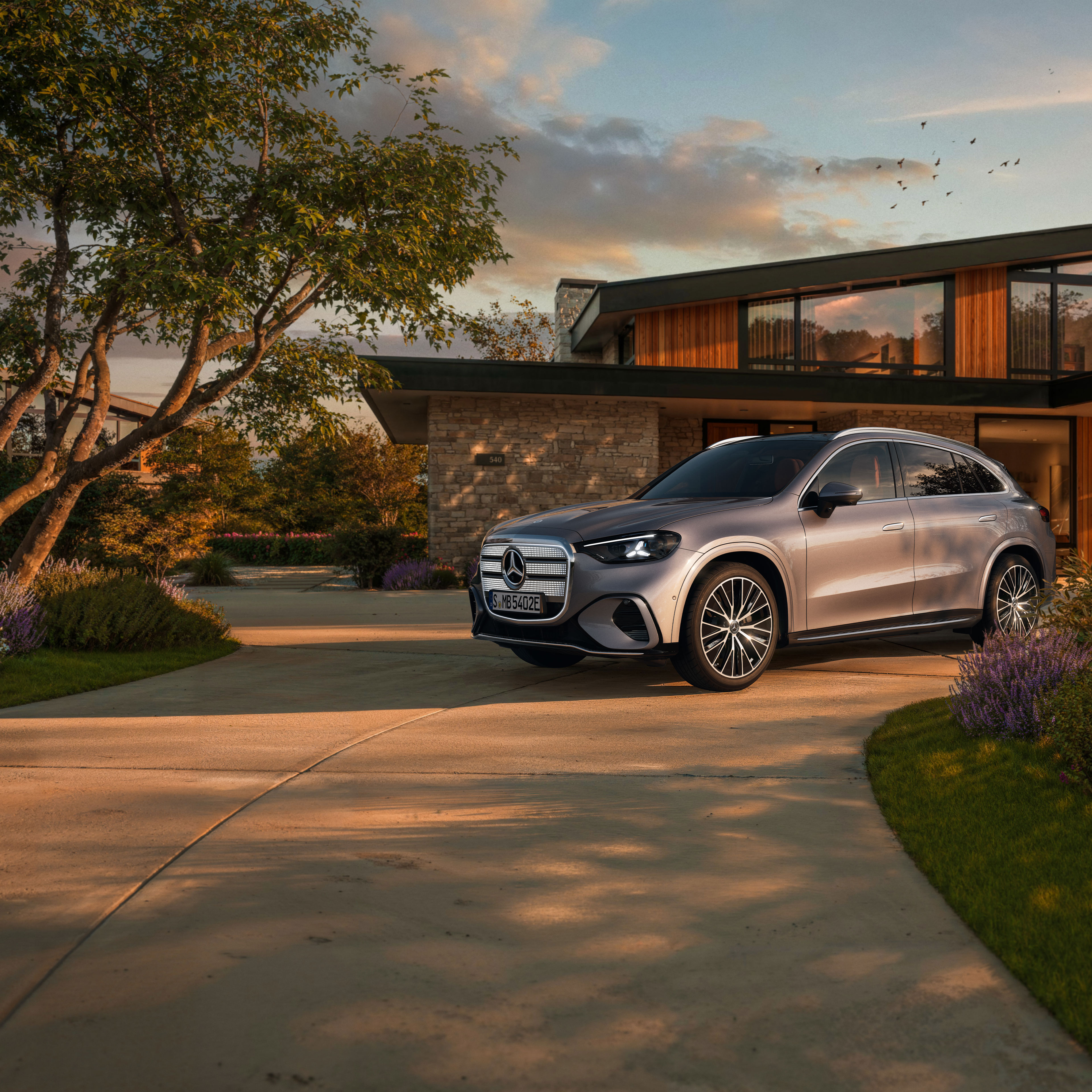 Visual lateral de un GLC eléctrico gris aparcado fuera de una casa