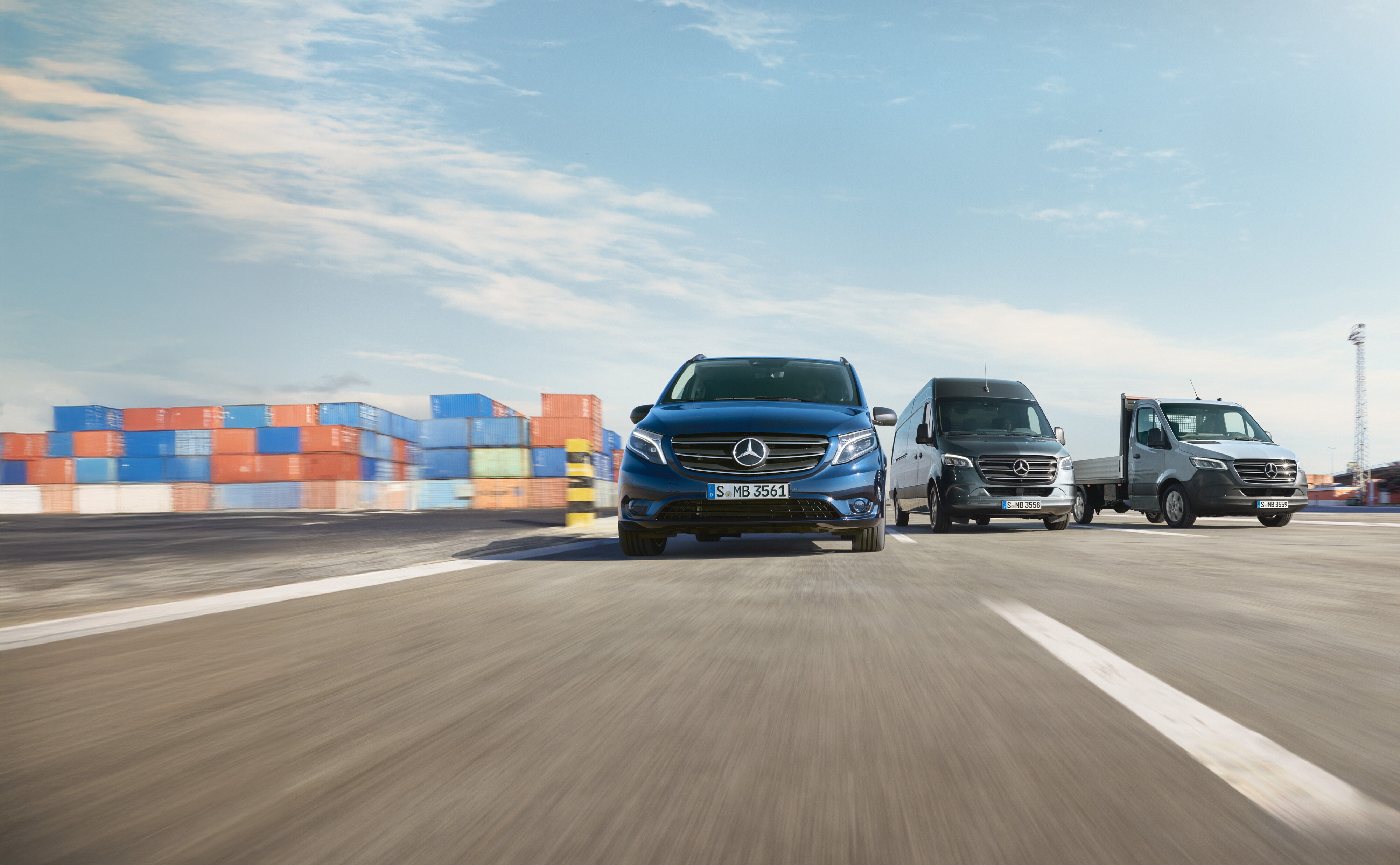 Mercedes-Benz | Cuidado de furgones | Service24h Varios furgones Mercedes-Benz aparcados lado a lado en una carretera junto a un muelle de carga.