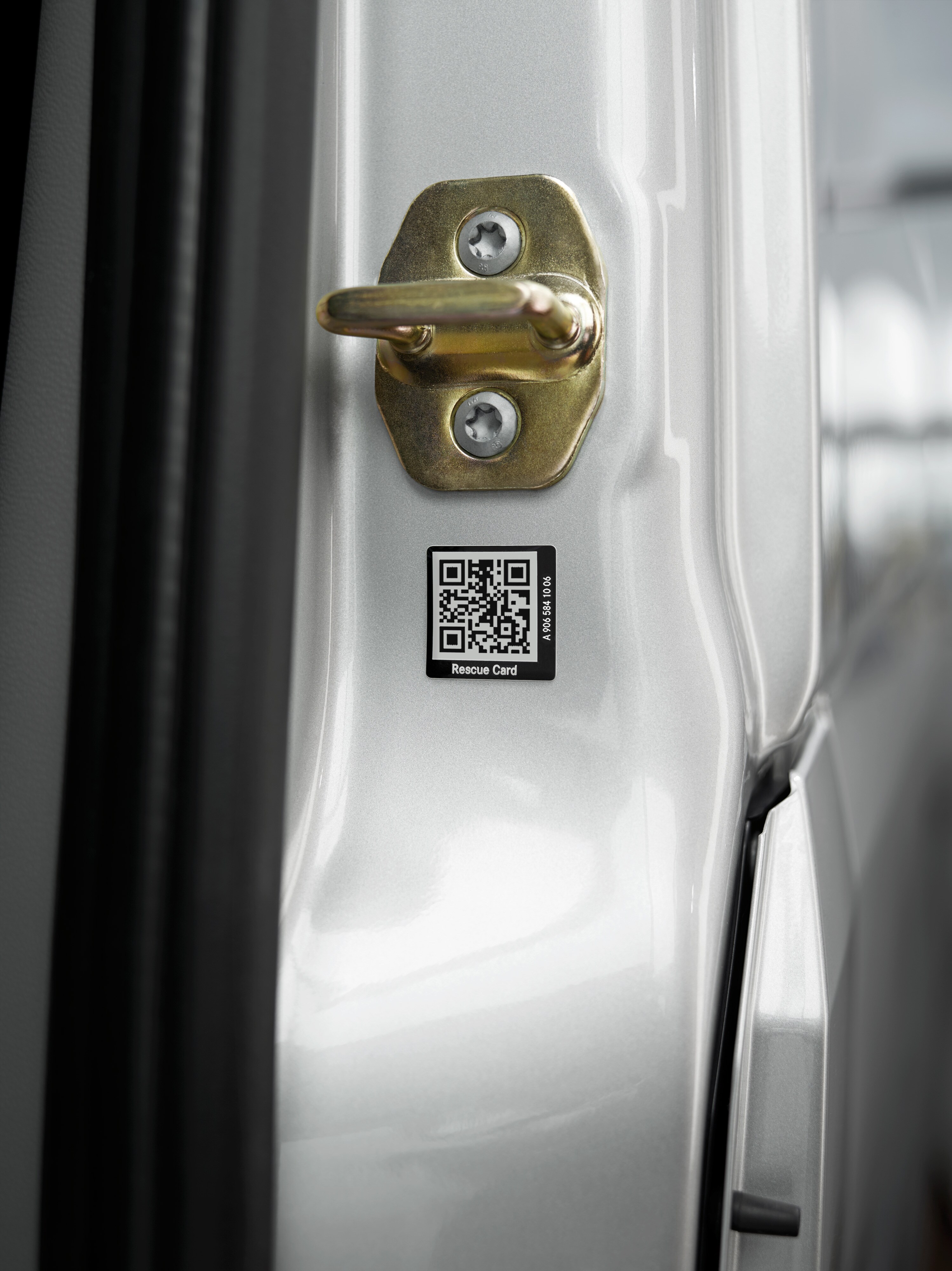 Mercedes-Benz | Cuidado de furgones | Pegatina de rescate Primer plano de una pegatina de tarjeta de rescate con código QR en la puerta del vehículo para una asistencia rápida en caso de emergencia.